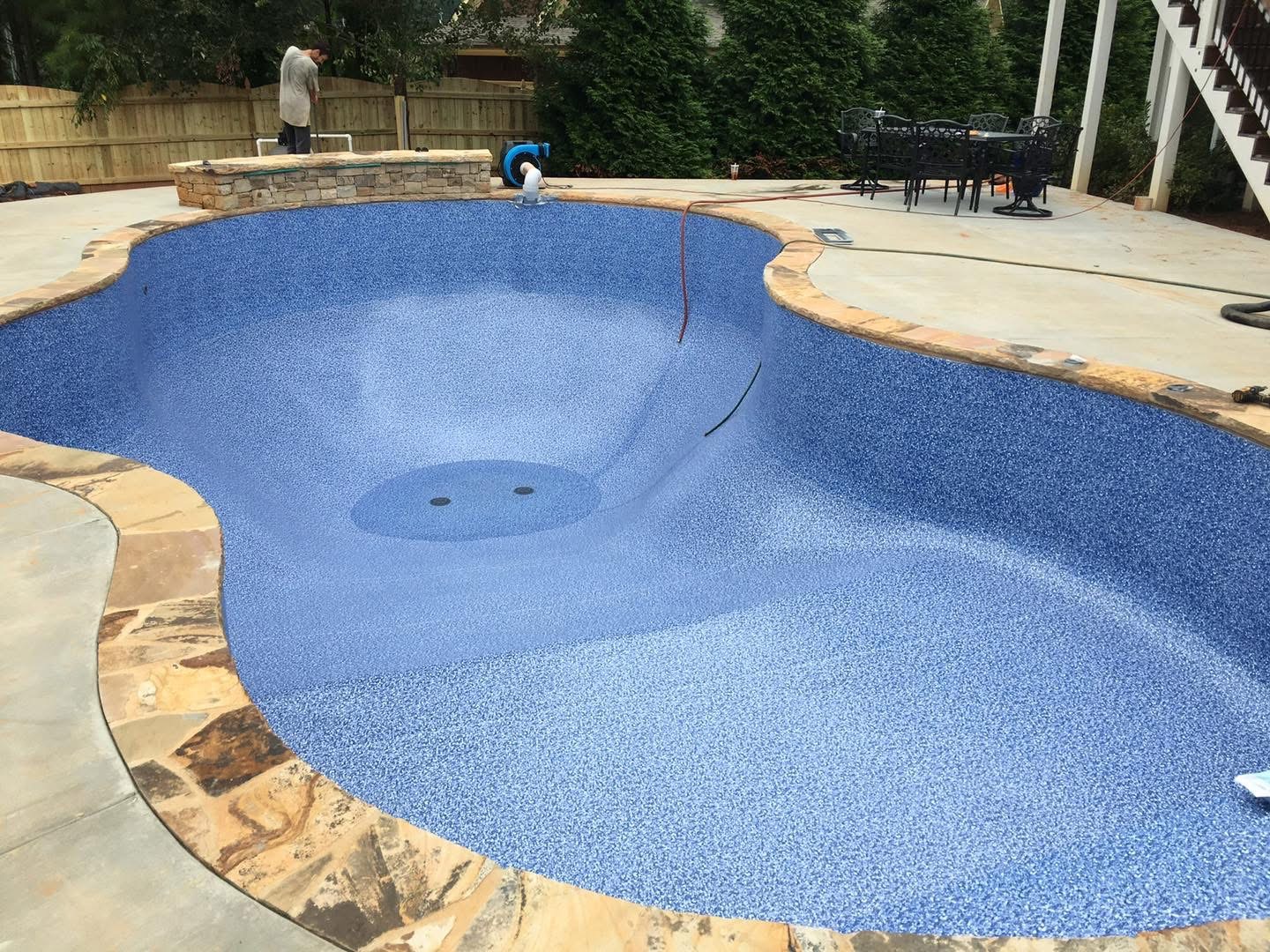 New vinyl liner being fitted in a residential pool beside a flagstone deck