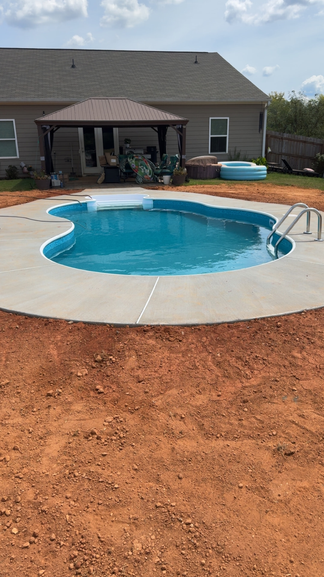 Freeform vinyl liner pool with white entry steps and a concrete deck