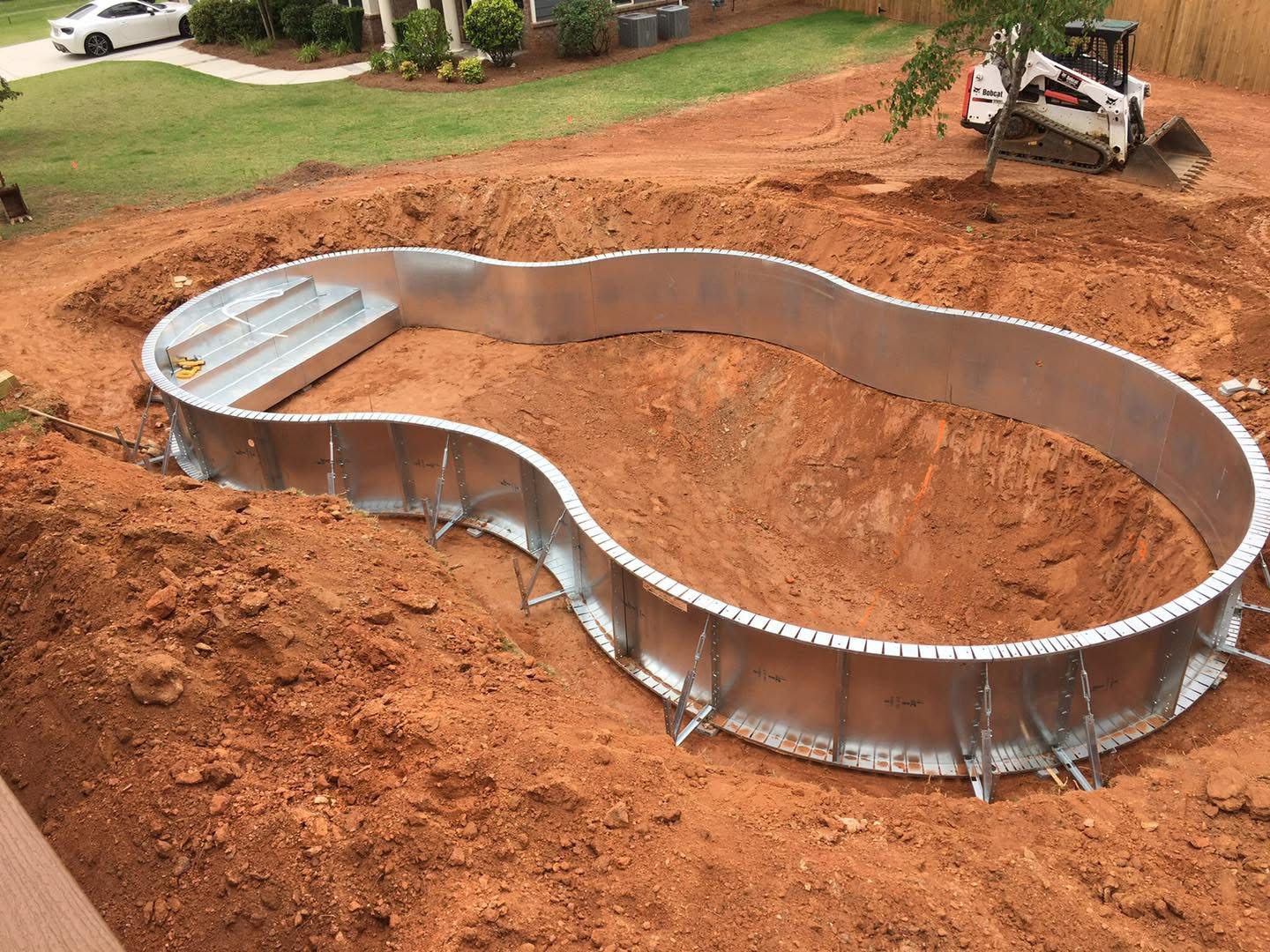 Steel pool walls and entry steps being set in an excavated Pickens County backyard